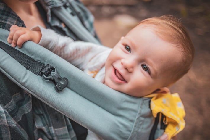 Bébé dans un porte-bébé souriant vers le ciel