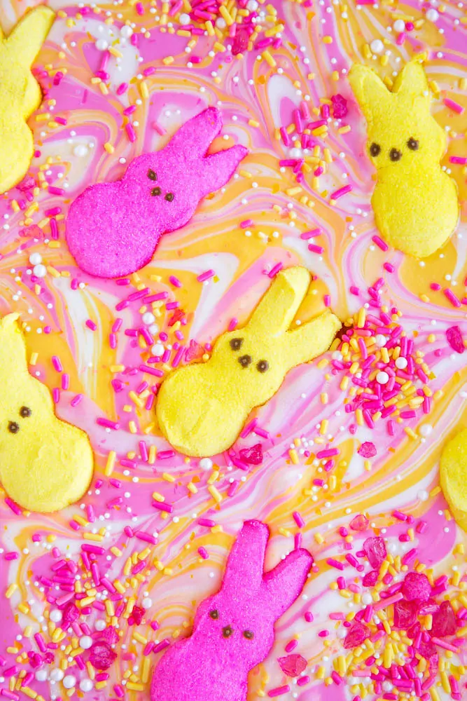Recette d'écorce de bonbon Peeps - des potes colorés roses et jaunes flottant dans une mer d'écorce de bonbon rose et jaune colorée avec des pépites
