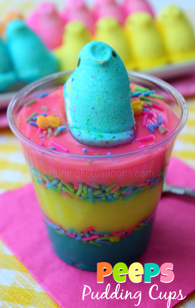 Tasses à pudding Peeps présentées dans une tasse transparente avec des couches de pudding brillant en rose, jaune et bleu avec des pépites entre les couches et un bonbon Peeps sur le dessus.