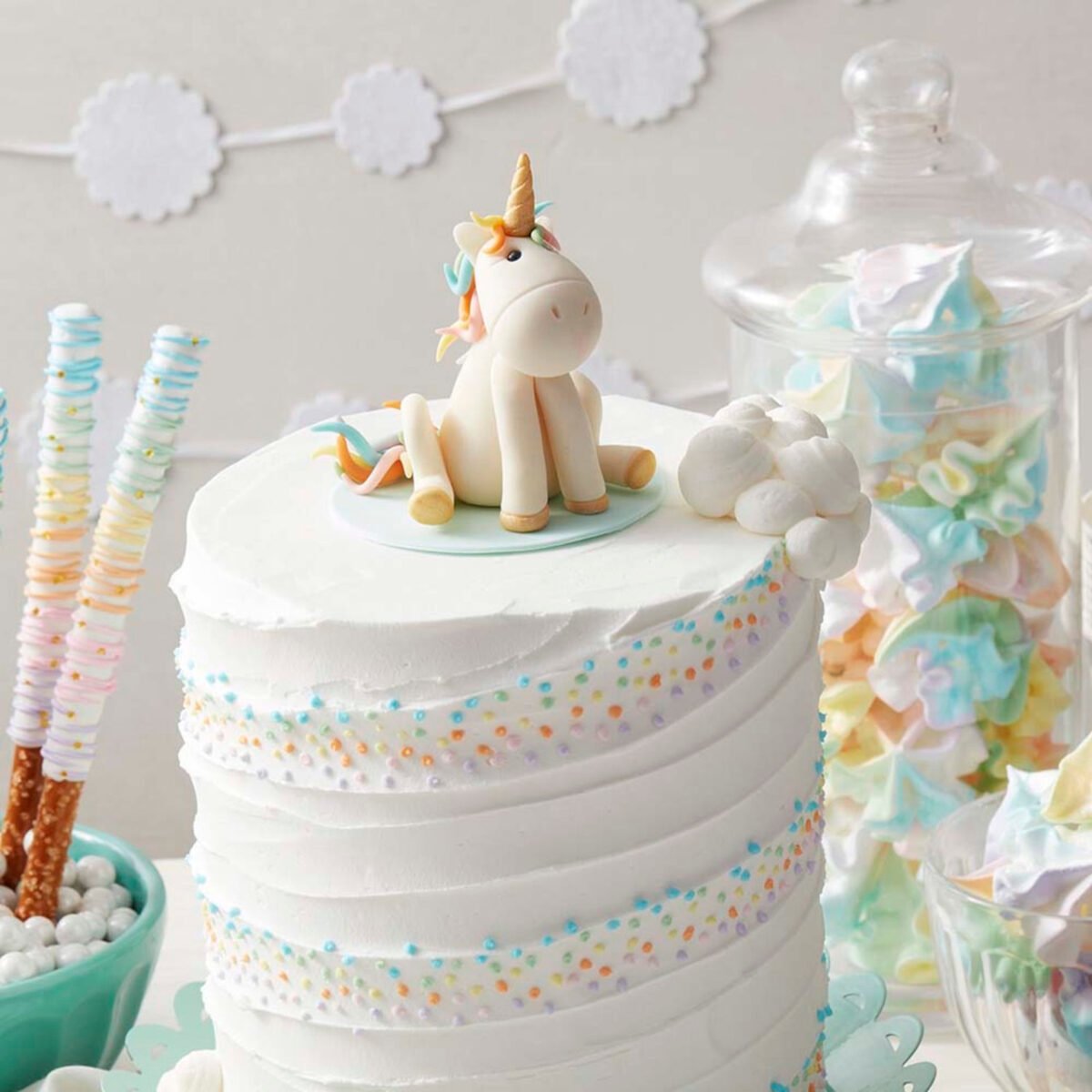 Gâteau blanc avec des arcs-en-ciel tourbillonnant à l'extérieur du gâteau - décoration licorne sur le dessus du gâteau