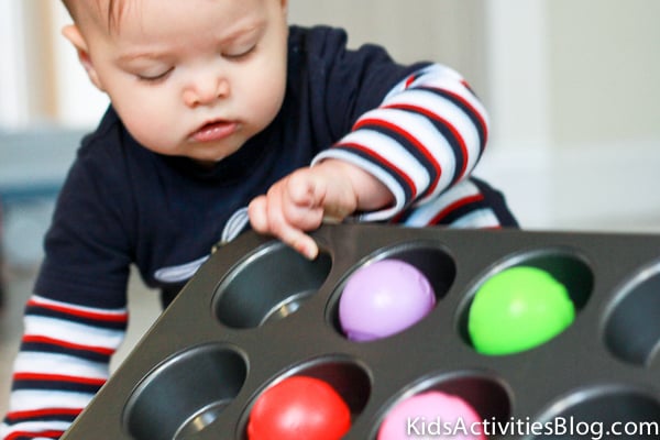 Activité de moules à muffins et de balles - bébé jouant avec un moule à muffins en métal et des boules en plastique arc-en-ciel - blog d'activités pour enfants