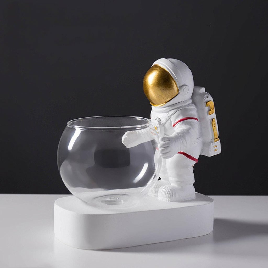 Astronaute doré tenant un vase transparent prêt à être planté sur un fond noir et blanc