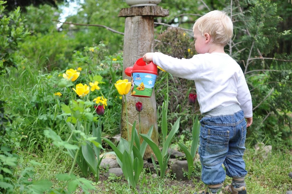 Tout-petit avec arrosoir travaillant dans le jardin