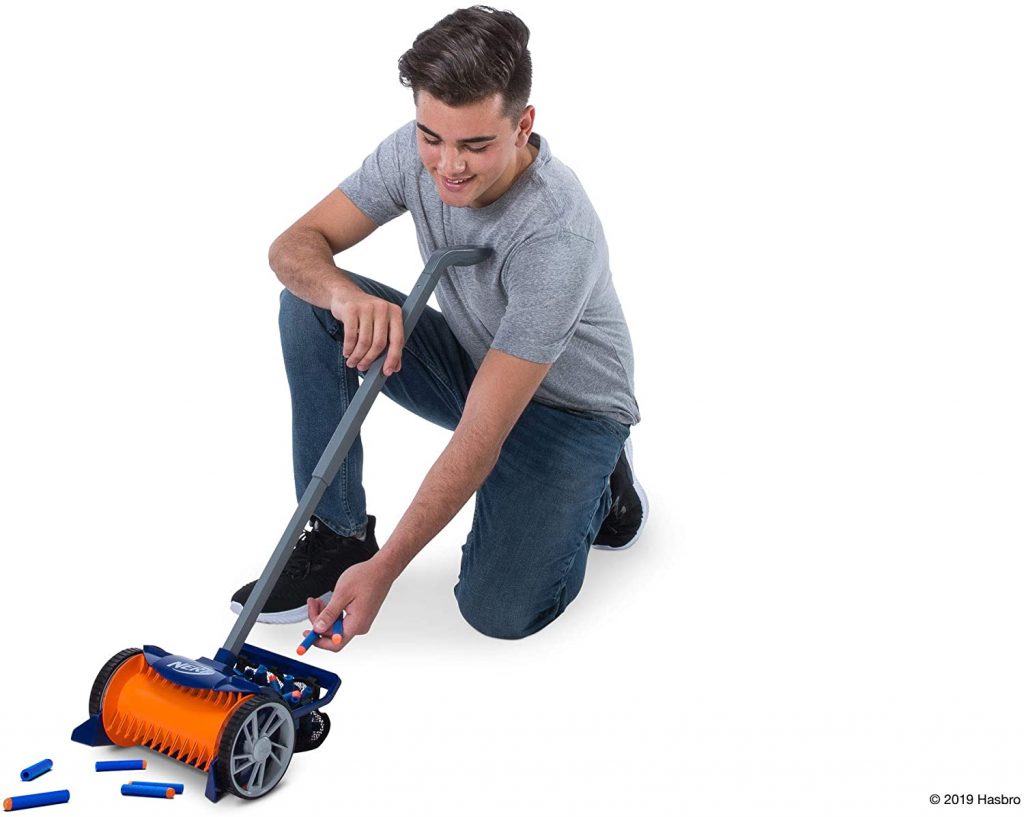 Le garçon vêtu d'un t-shirt gris et d'un jean est en train de sortir les fléchettes nerf du panier à l'arrière de l'aspirateur nerf.