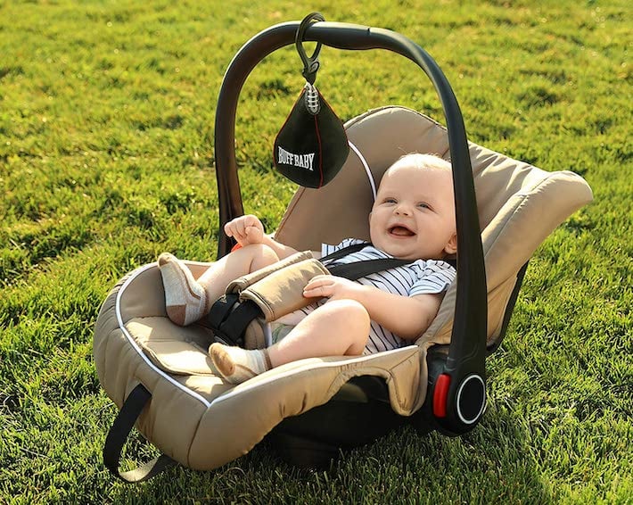 Jouet suspendu pour siège d'auto sur une sangle de siège d'auto sur un bébé à l'extérieur dans l'herbe