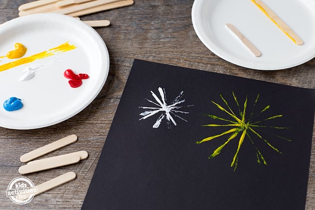 Étapes 1 à 3 - Artisanat de feux d'artifice - Trempez vos bâtons de popsicle dans la peinture et tamponnez-les sur le papier de construction noir.