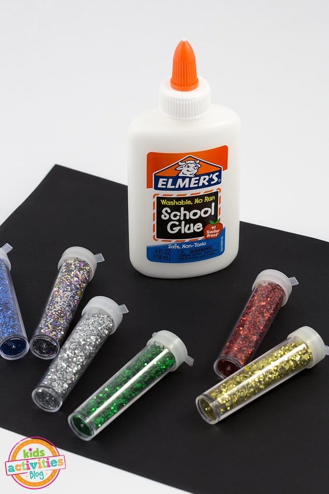 Art de feux d'artifice - Fournitures nécessaires pour fabriquer des feux d'artifice comme : de la colle Elmer's, des tubes de paillettes et du papier de construction noir sur fond blanc - Blog d'activités pour enfants
