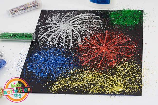 Art des feux d'artifice - Étape 2 - saupoudrez les paillettes sur la colle sur le papier de construction noir - Blog d'activités pour les enfants