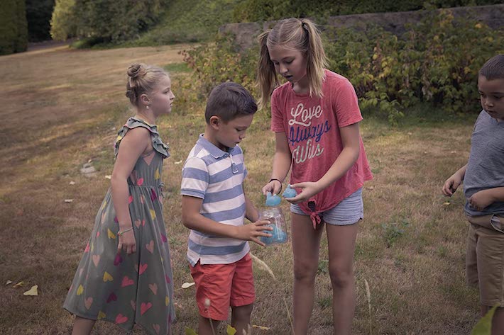 Jeu de chasse aux lucioles joué par 2 garçons et 2 filles qui allument les lucioles dans un bocal