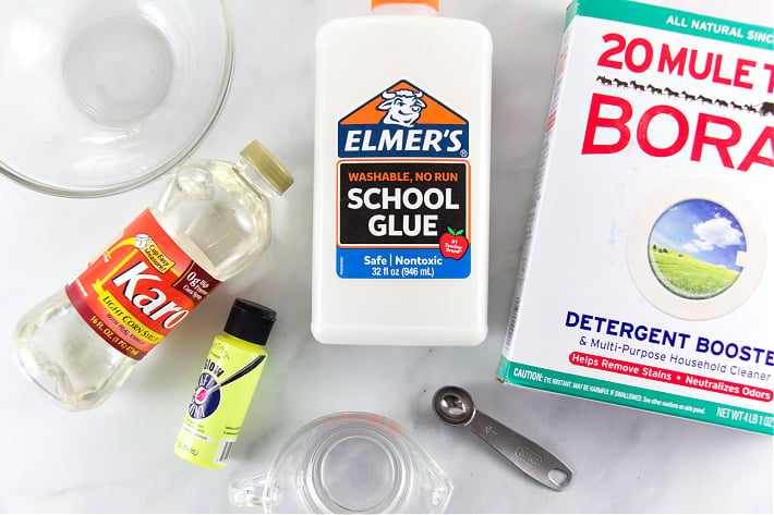 Recette de slime qui brille dans le noir : borax, colle scolaire d'Elmer, sirop de maïs et peinture sur une table pour réaliser un projet d'artisanat