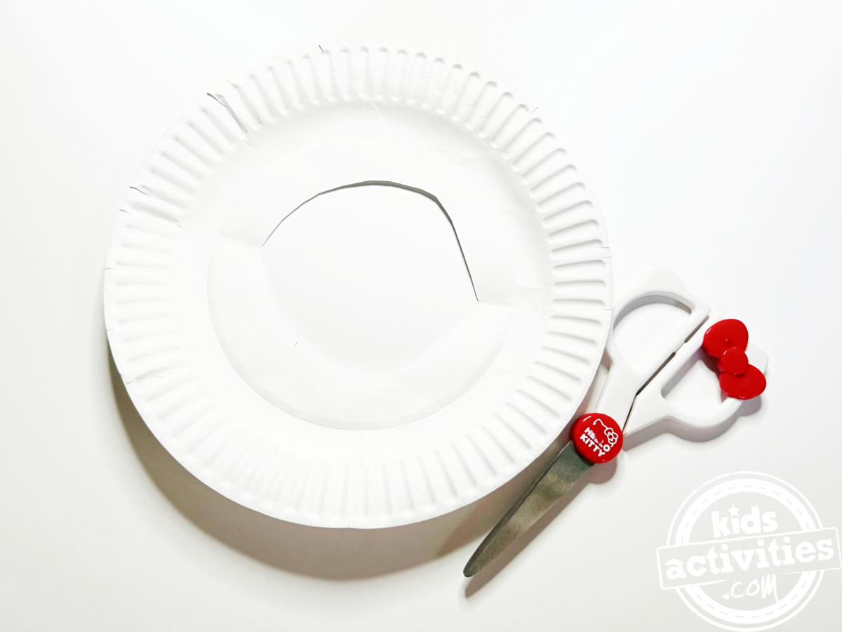 Étape 1 - Bricolage avec une assiette en carton en forme de beignet - Découpez un cercle à l'intérieur de l'assiette en carton avec des ciseaux - Blog d'activités pour enfants