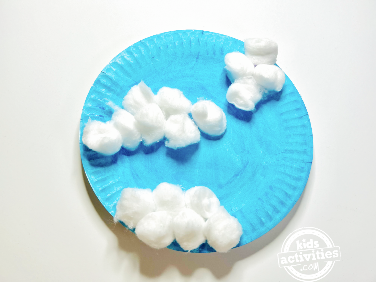 Bricolage terminé - Bricolage avec une assiette en carton représentant un ciel nuageux - Une assiette en carton finie peinte en bleu avec des boules de coton en forme de ciel collées dessus - Blog d'activités pour enfants