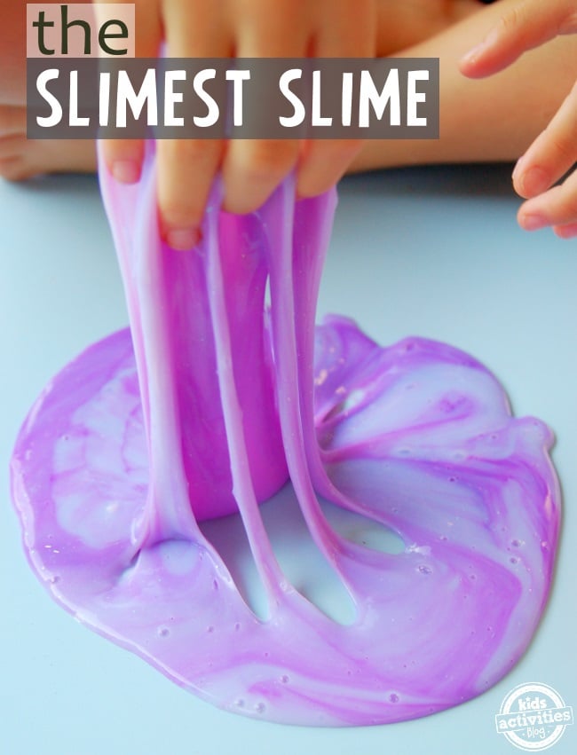 Slime lumineux - la recette de slime la plus gluante - slime violet retiré d'une surface de table bleue avec les mains des enfants - Blog d'activités pour enfants