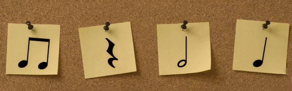 L'image montre des notes de musique sur des notes autocollantes sur un mur. 