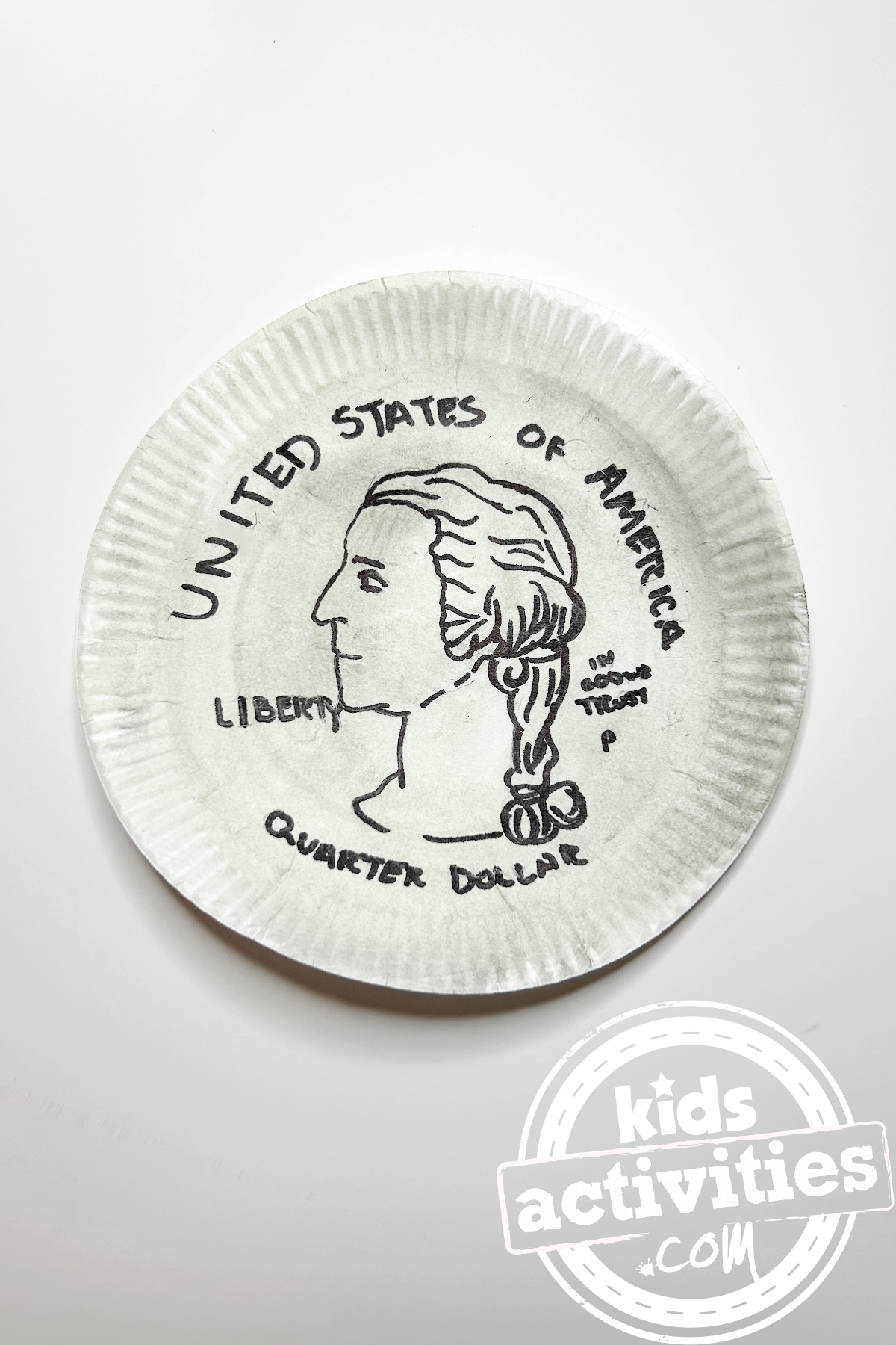Bricolage d'un quart de dollar terminé sur une assiette en papier peinte en argent avec le dessin d'un quart de dollar dessus sur un fond blanc - blog d'activités pour enfants