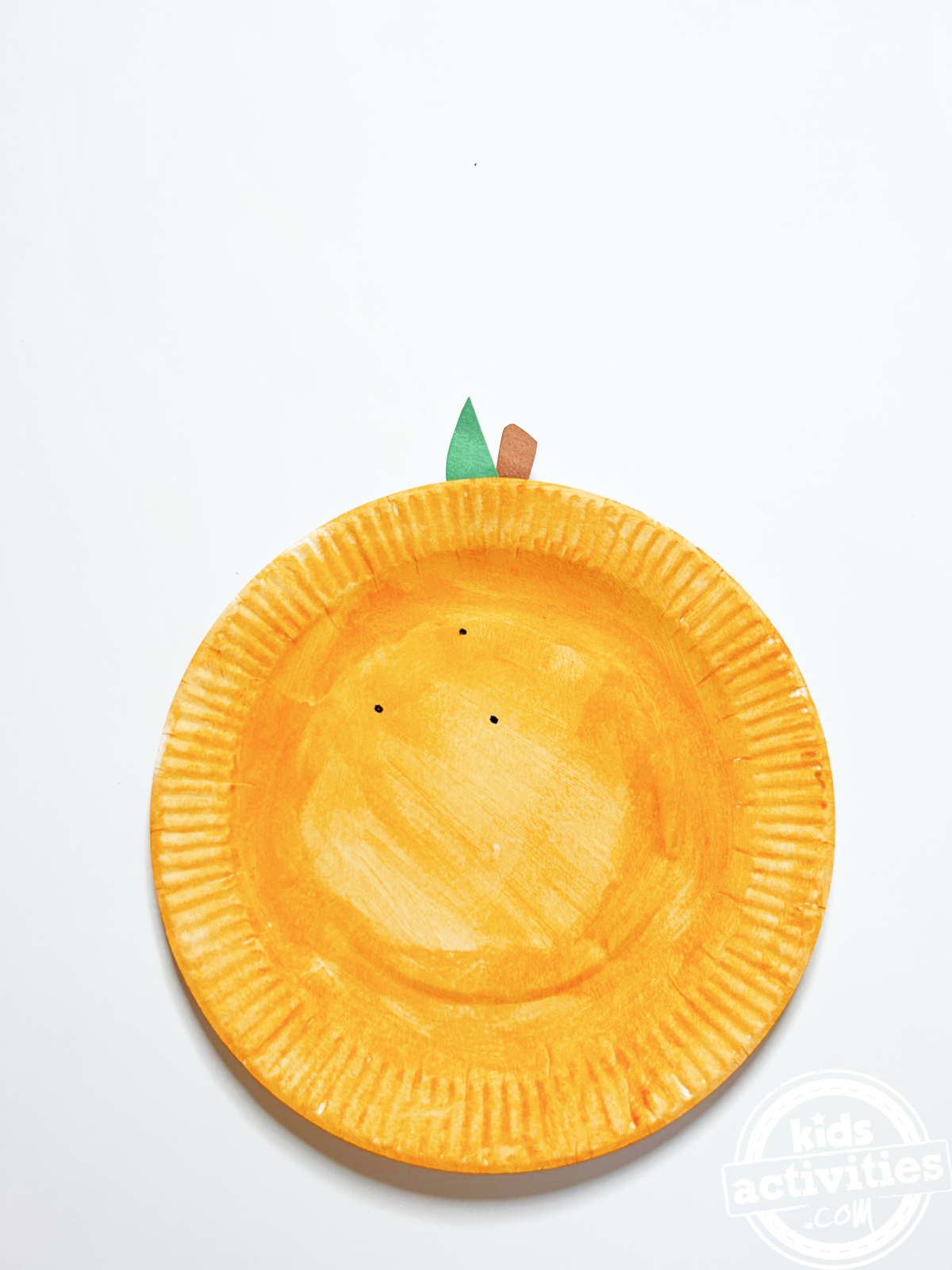 Bricolage final en assiette en carton orange avec feuille verte et tige marron - blog d'activités pour enfants