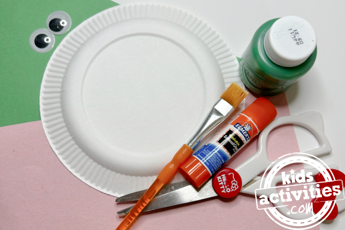 Fournitures nécessaires pour le bricolage de la tortue en assiette en carton : du papier de construction vert et rose, une mini assiette en carton, de la peinture verte, des yeux mobiles, de la colle, des ciseaux et un pinceau - Blog d'activités pour enfants