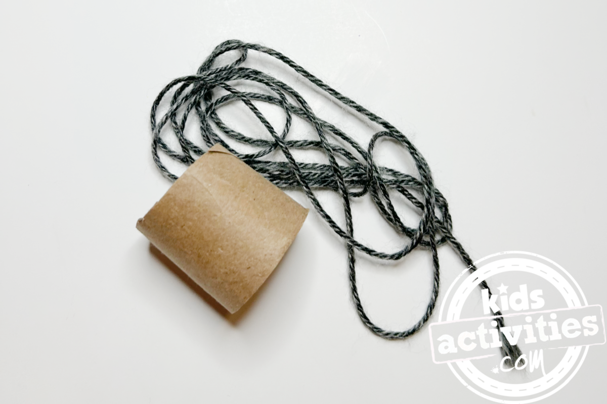 Étape 3 - Bricolage avec une assiette en papier Yo-yo - Enroulez une partie de la ficelle autour du milieu du tube coupé et nouez-la. Assurez-vous d'enrouler un peu plus de ficelle après coup sans la nouer ! - Blog d'activités pour enfants