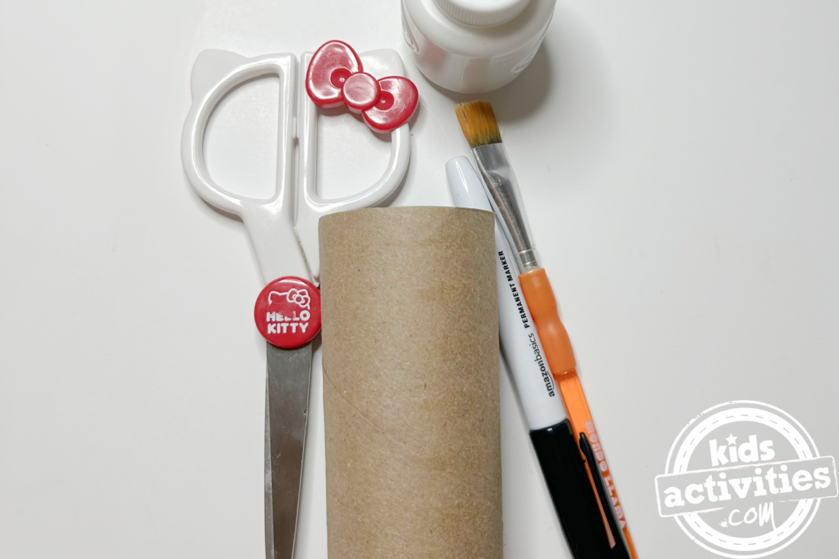 Fournitures nécessaires pour le bricolage du rouleau de papier toilette fantôme : un rouleau de papier toilette, de la peinture blanche, un feutre et un pinceau - Blog d'activités pour enfants