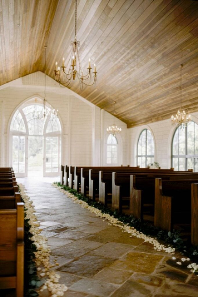 Allée de mariage minimaliste avec verdure et bancs en bois.