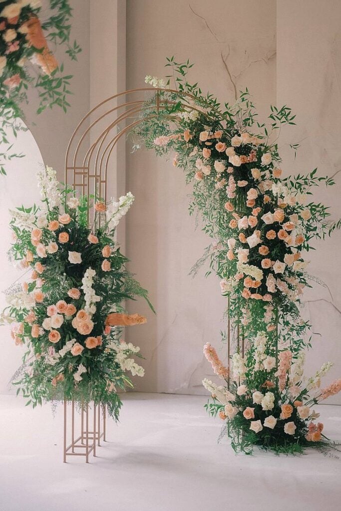 Arche florale élégante avec roses pastel et verdure pour micro mariage.