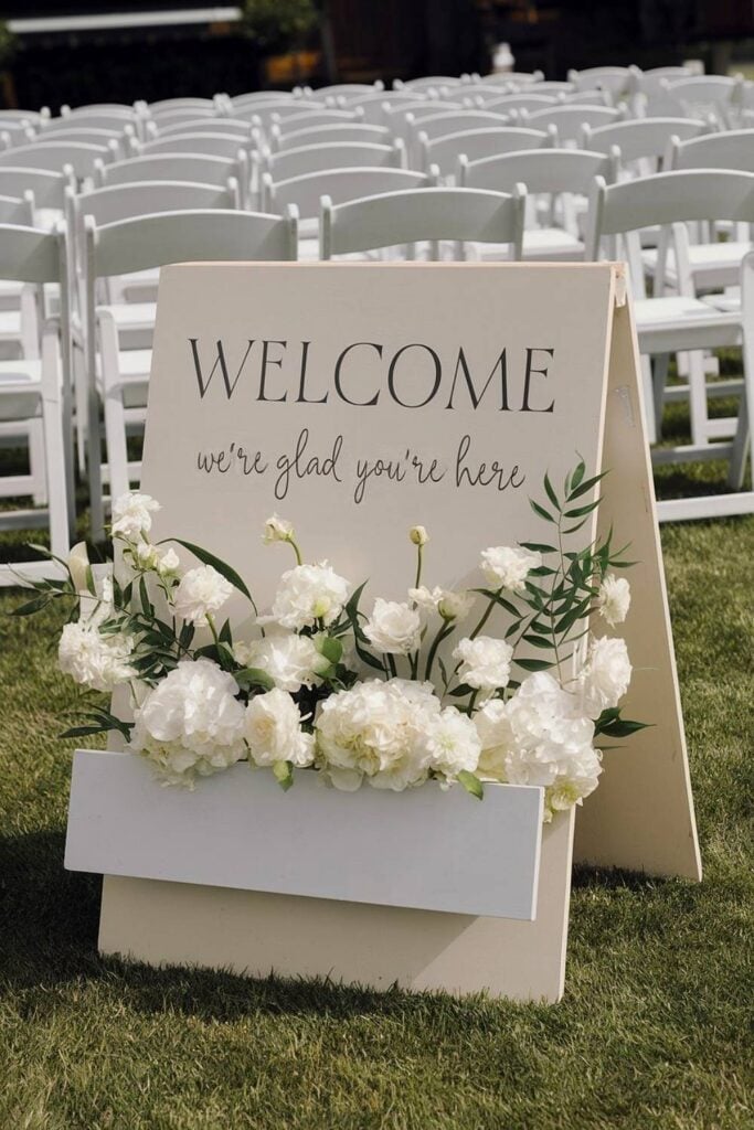 Panneau de bienvenue avec fleurs blanches et verdure au micro-mariage.