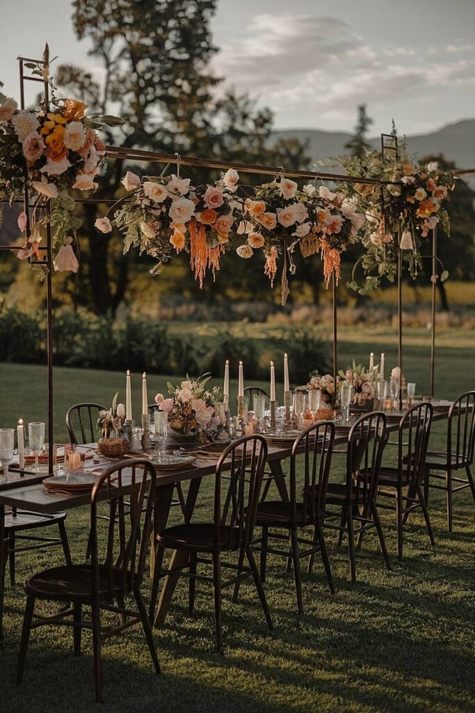 Table de mariage extérieure intime avec fleurs suspendues et bougies.
