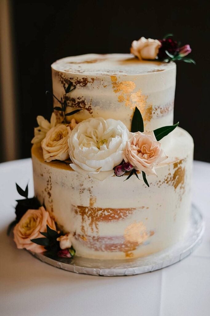 Petit gâteau de mariage élégant avec des accents dorés et des fleurs.