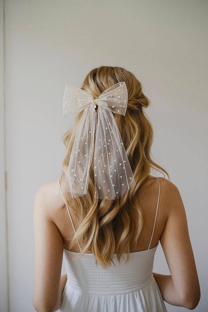 Coiffure de mariée mi-haute avec nœud à pois.