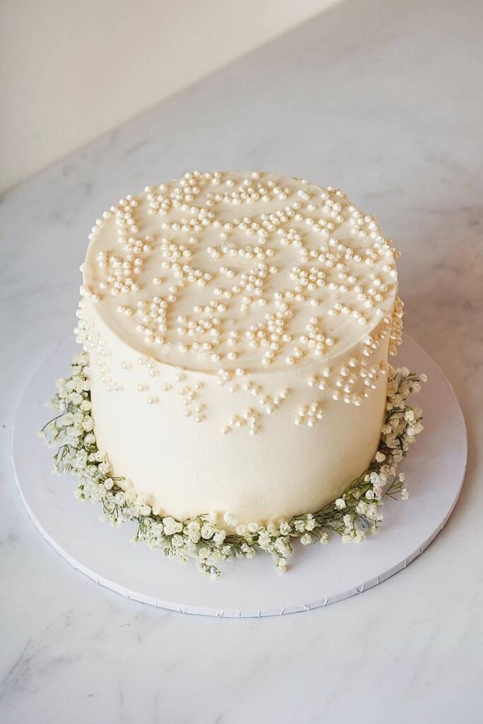 Gâteau de douche nuptiale minimaliste avec des perles et du souffle de bébé.