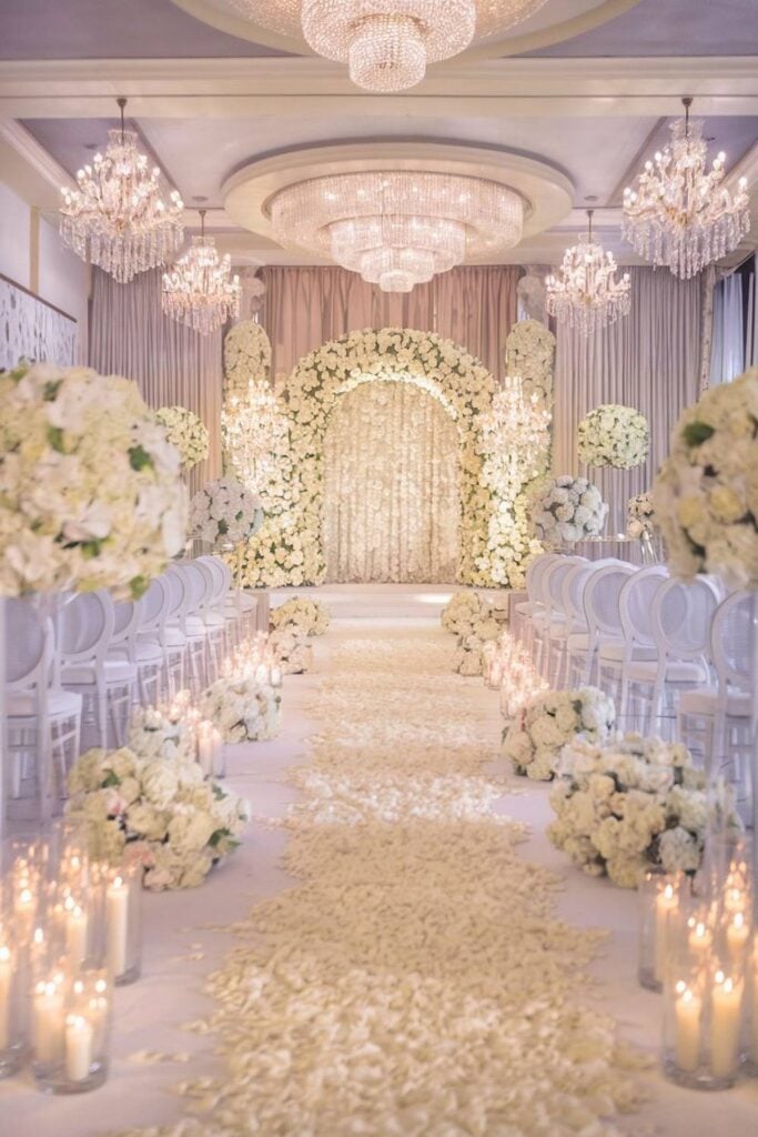 Allée de mariage de luxe avec tapis moelleux et compositions florales imposantes.