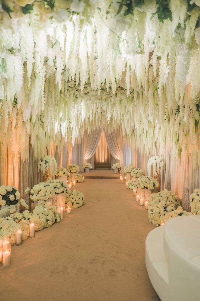 Grande entrée de mariage de luxe avec fleurs blanches en cascade et bougies.
