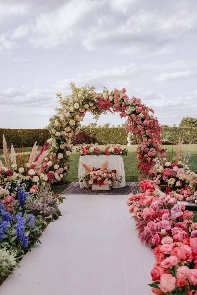 Arche florale avec fleurs roses et blanches pour autel de mariage dans la cour.