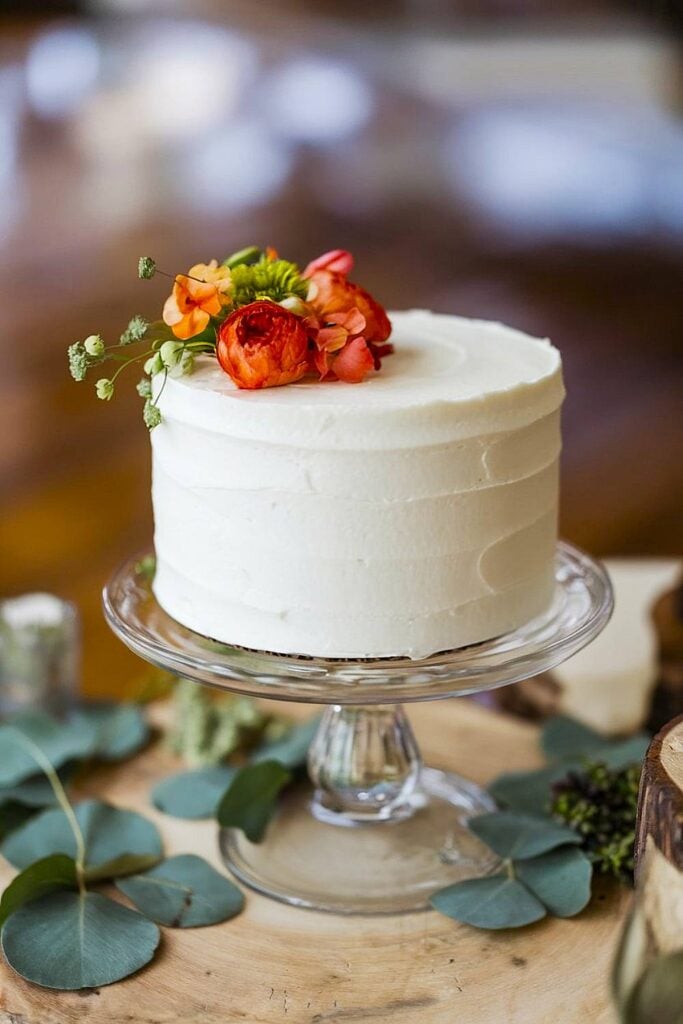 Gâteau minimaliste à un étage avec des fleurs fraîches pour un mariage dans la cour.