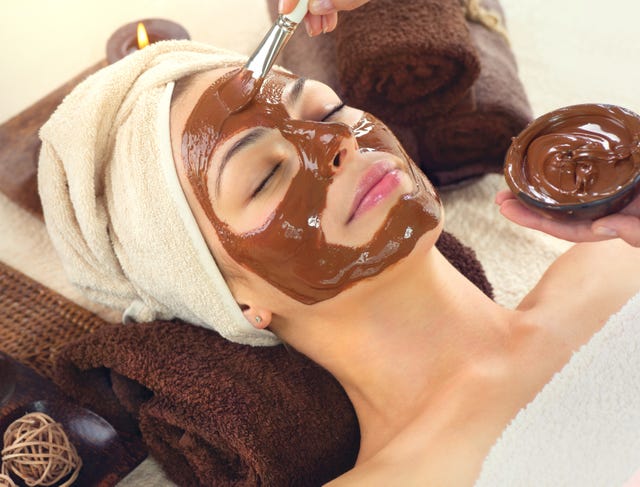 Spa de luxe au chocolat. masque facial. Belle jeune femme se détendant dans le salon de spa de beauté, appliquant un masque de visage au chocolat.599513765