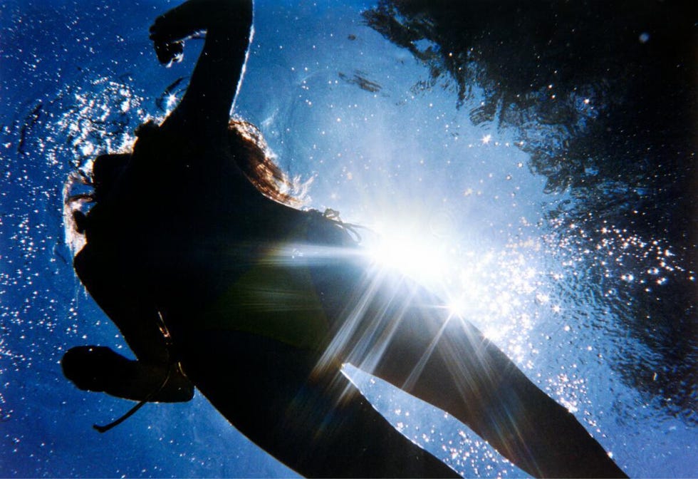 Une silhouette d'une personne sous l'eau avec la lumière du soleil se reflétant sur la surface.