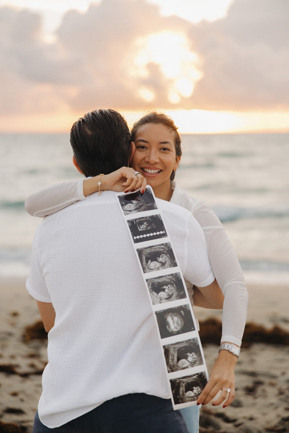 Couple profitant d'un coucher de soleil sur la plage, affichant des images échographiques.