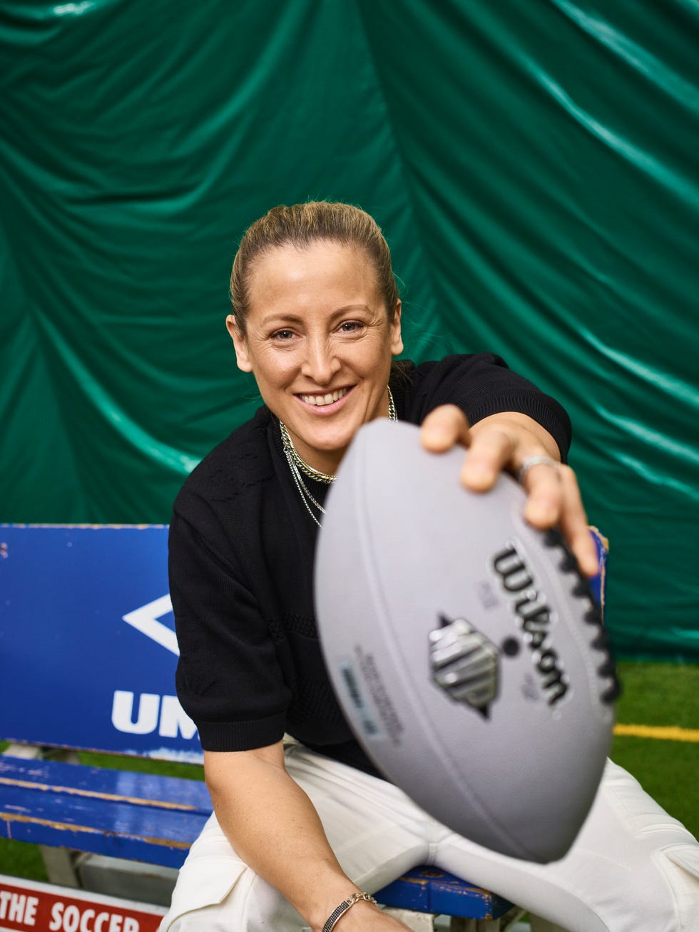 Individu tenant un ballon de football dans un cadre sportif.